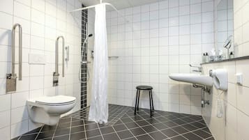 A modern bathroom with a toilet, a shower with a white curtain, a sink, and a small stool.