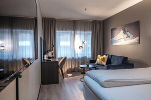Una camera d'albergo con un letto, una scrivania con una sedia, un tavolino e un divano.