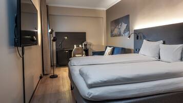 A hotel room with a large bed, a desk, a chair, a flat-screen TV, and a painting on the wall.