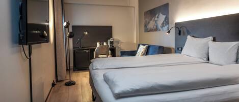 Une chambre d’hôtel avec un grand lit, un bureau, une chaise, un téléviseur à écran plat et un tableau au mur.