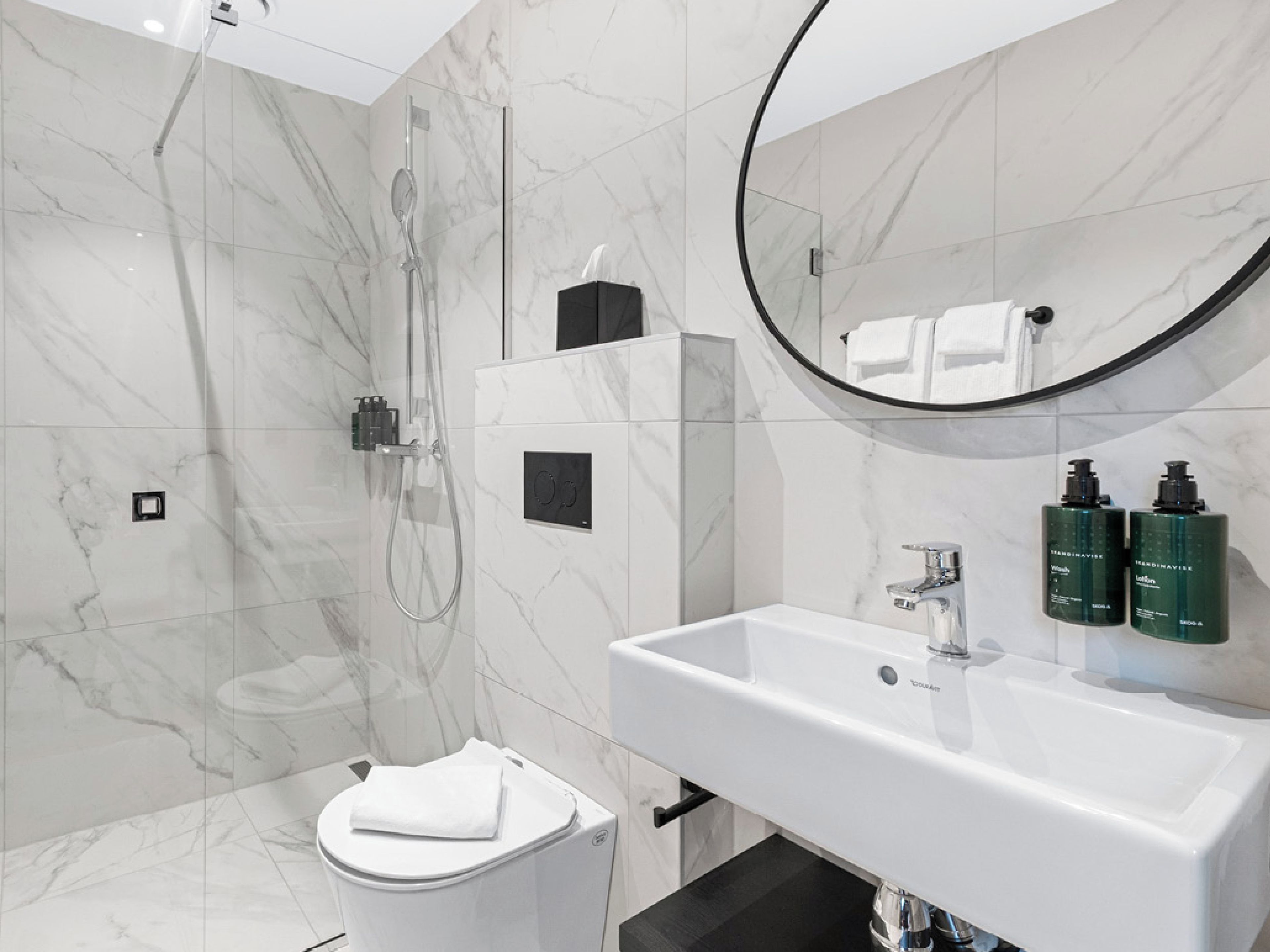 Une salle de bain moderne équipée d’une douche, de toilettes, d’un lavabo et d’un miroir.