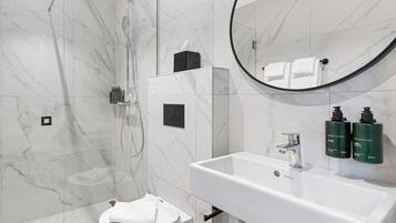 Une salle de bain moderne équipée d’une douche, de toilettes, d’un lavabo et d’un miroir.