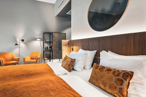 A modern hotel room with a large bed, two chairs, a wardrobe, and a round mirror on the wall. - Karl Johan Hotel (Oslo)