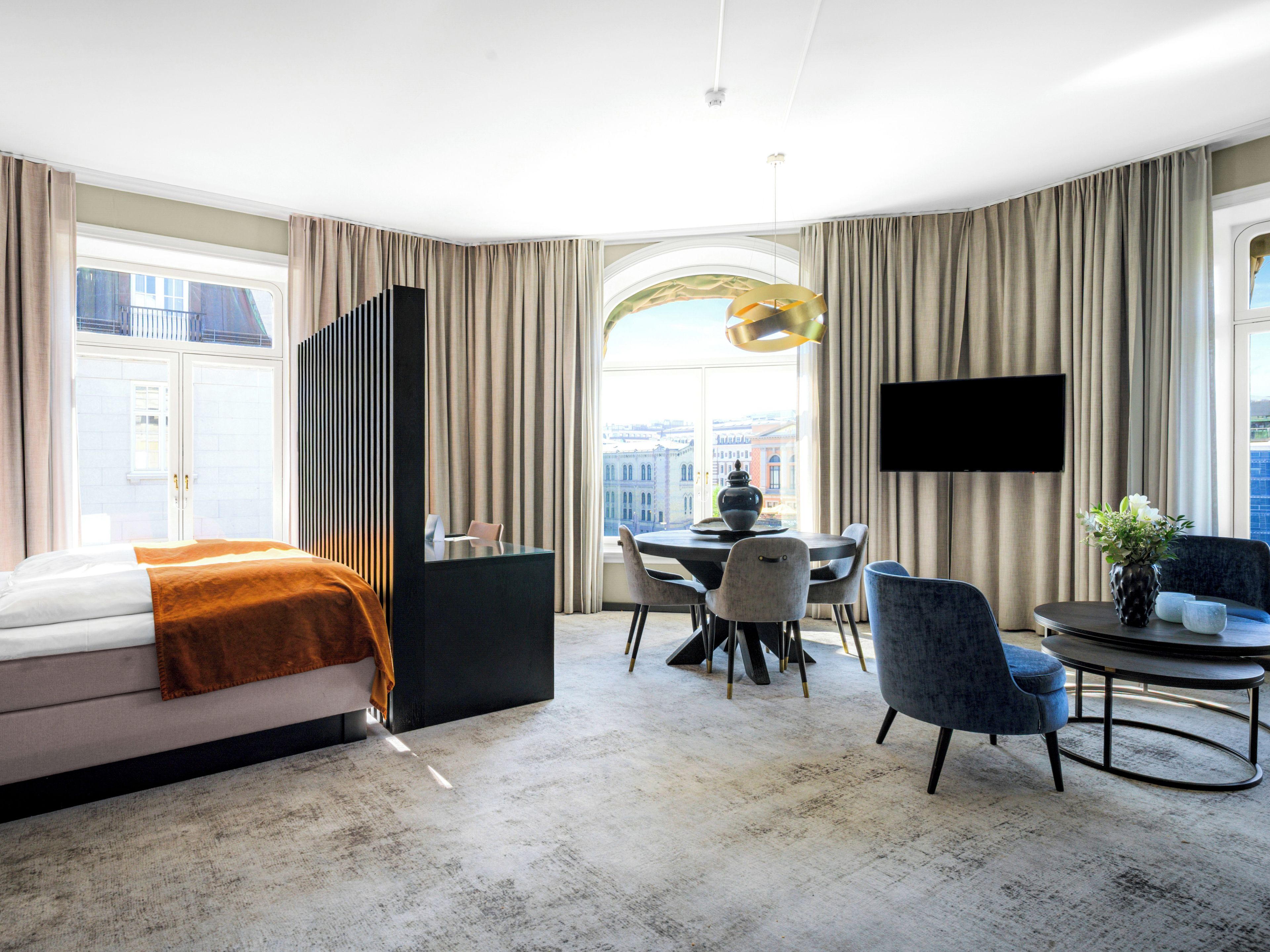 Una habitación de hotel moderna con cama, zona de comedor y televisor.