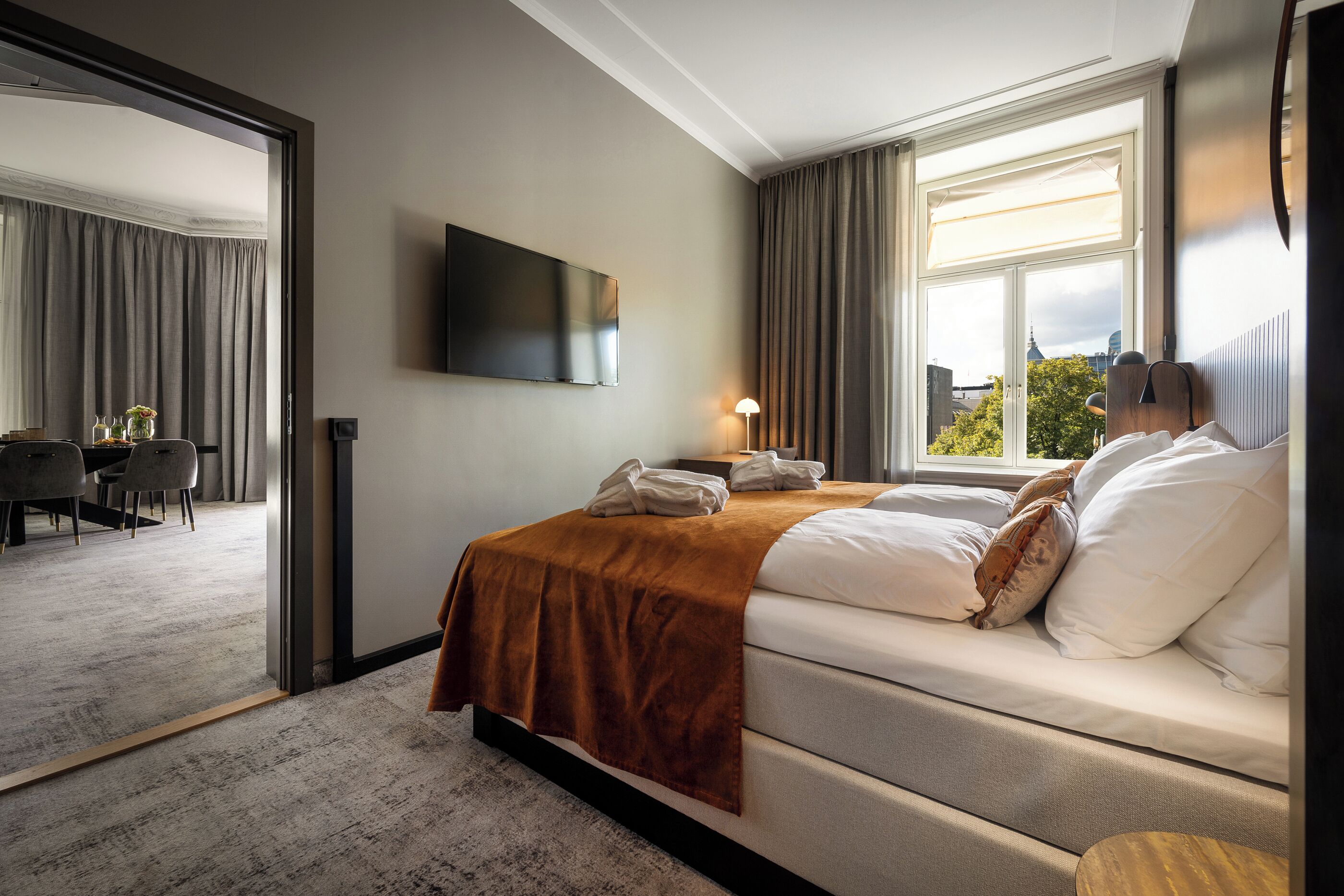 Een moderne hotelkamer met een groot bed, een flatscreen televisie en uitzicht op de stad.