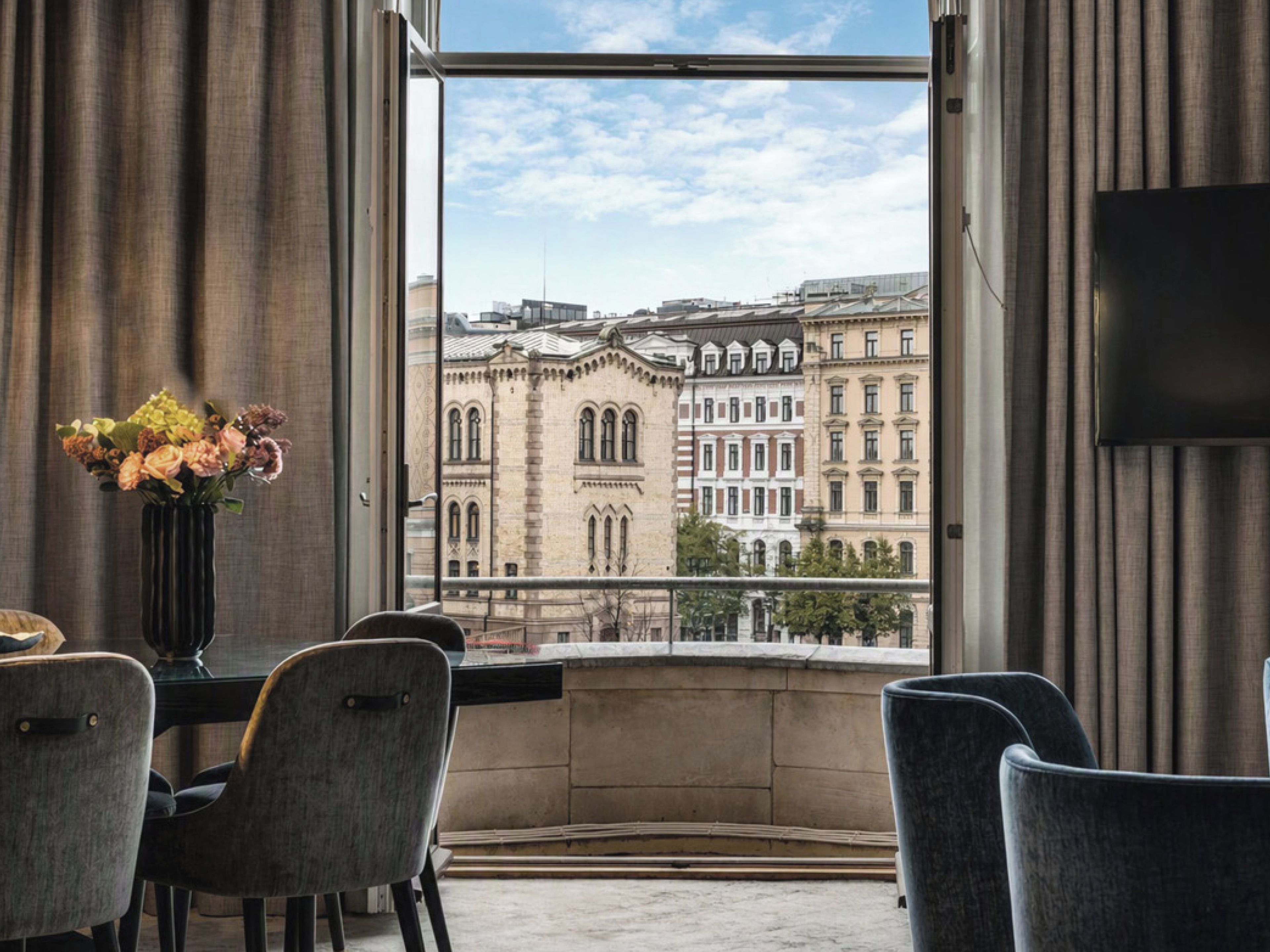 Habitación de hotel con un ventanal grande con vistas a edificios históricos.