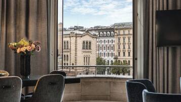 Habitación de hotel con un ventanal grande con vistas a edificios históricos.