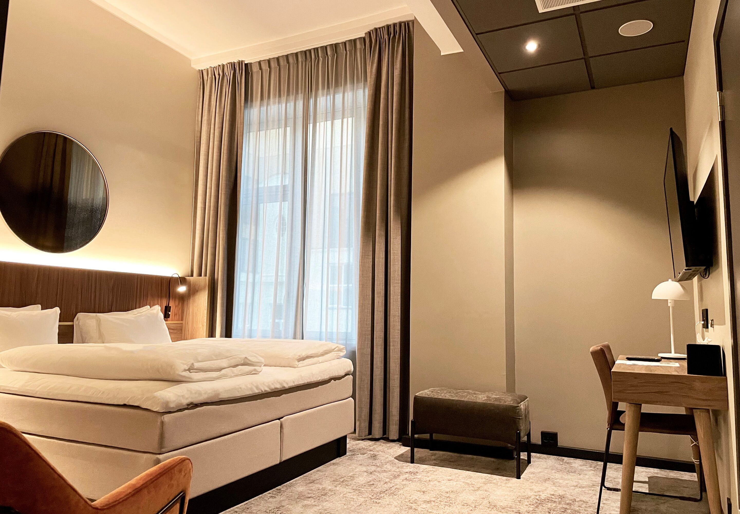 Una habitación de hotel moderna con una cama grande, un escritorio, una silla y un televisor.