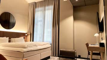 Una habitación de hotel moderna con una cama grande, un escritorio, una silla y un televisor.
