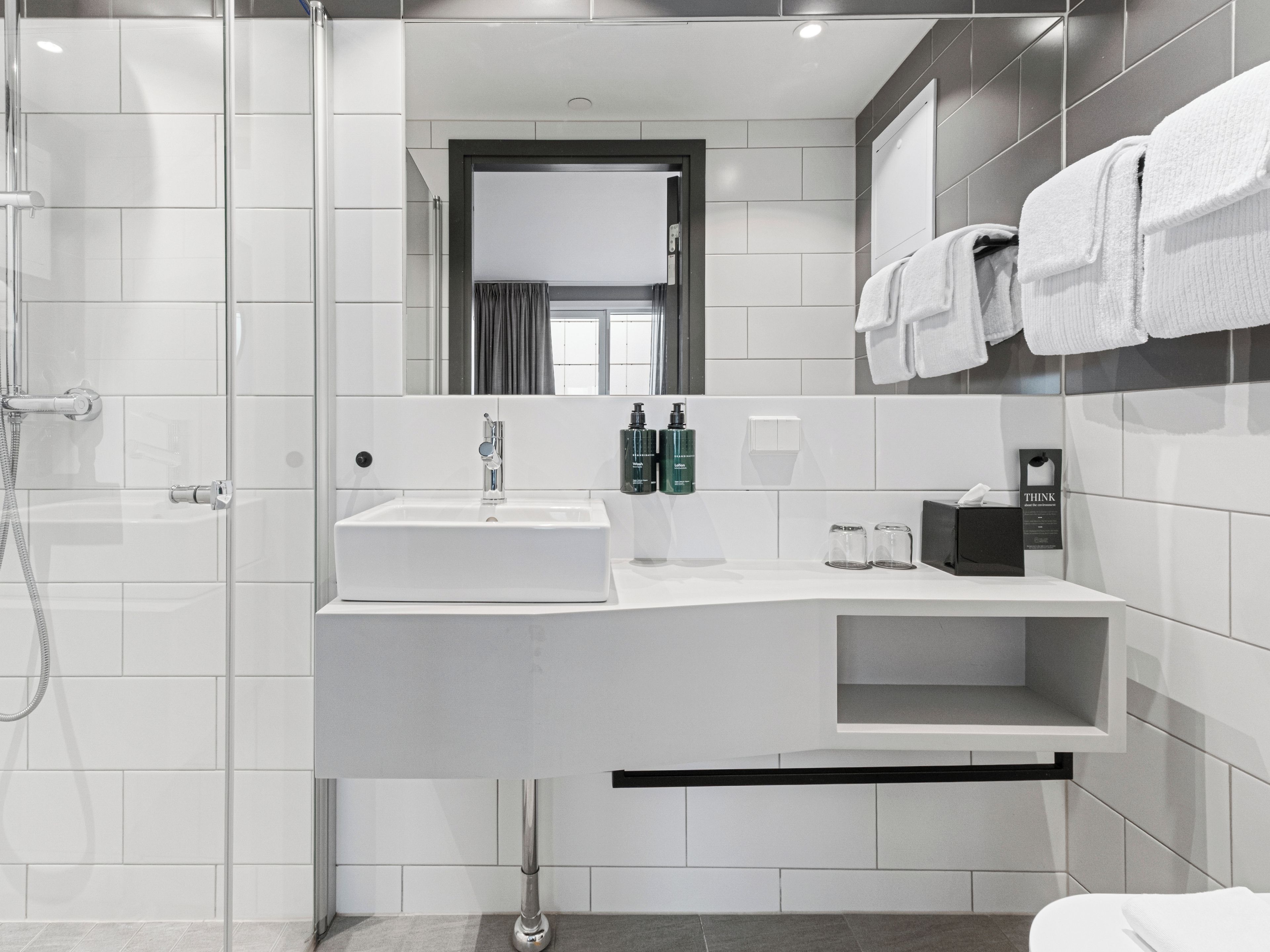 A modern bathroom with a shower, a sink, and a mirror.