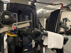 Un gimnasio con equipo de ejercicio, incluyendo una prensa de banca y una torre de pesas.