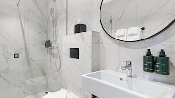 Un baño moderno con ducha, inodoro, lavabo y dispensadores de gel antibacterial.