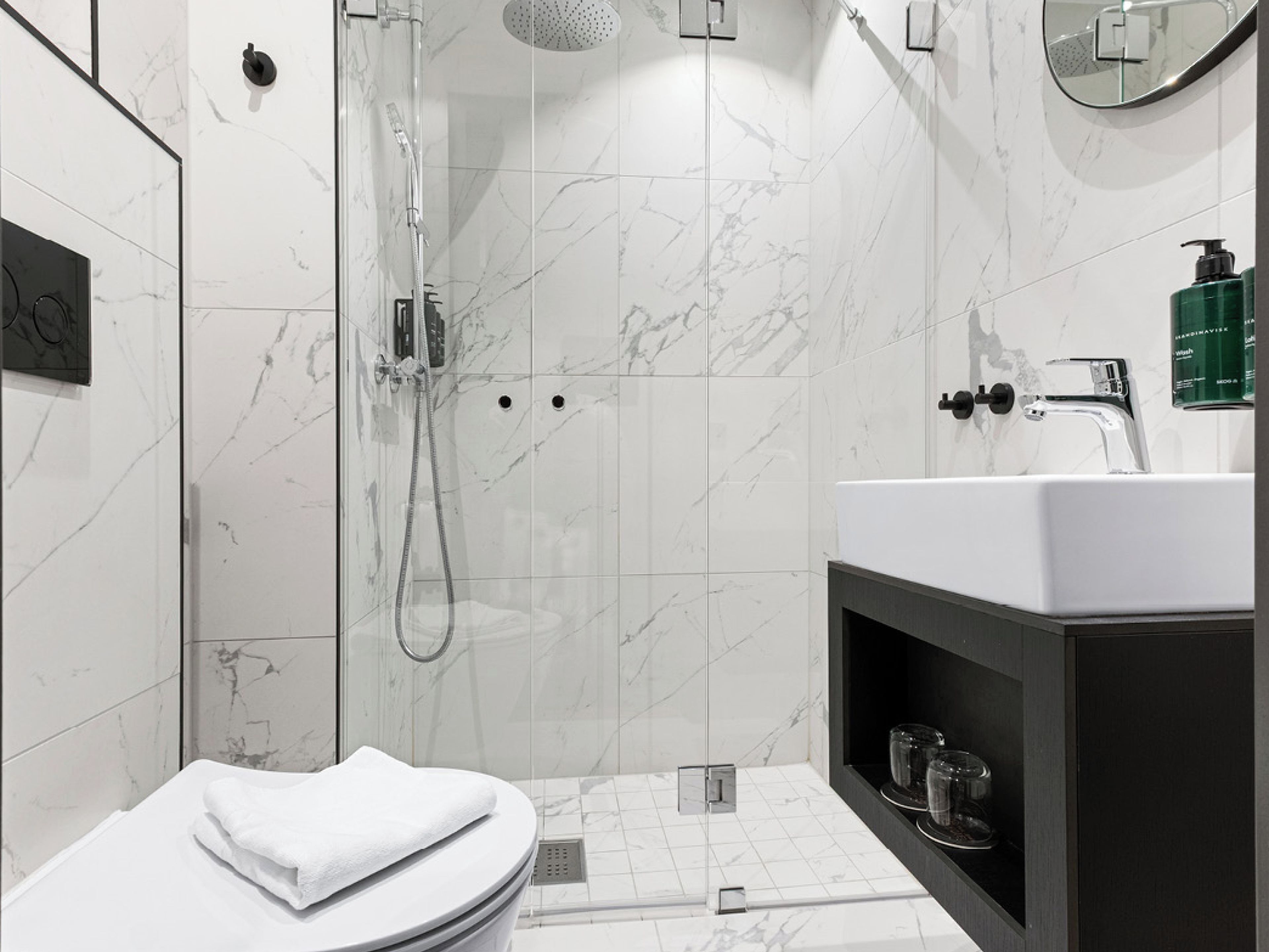 A modern bathroom with a shower, toilet, and sink.