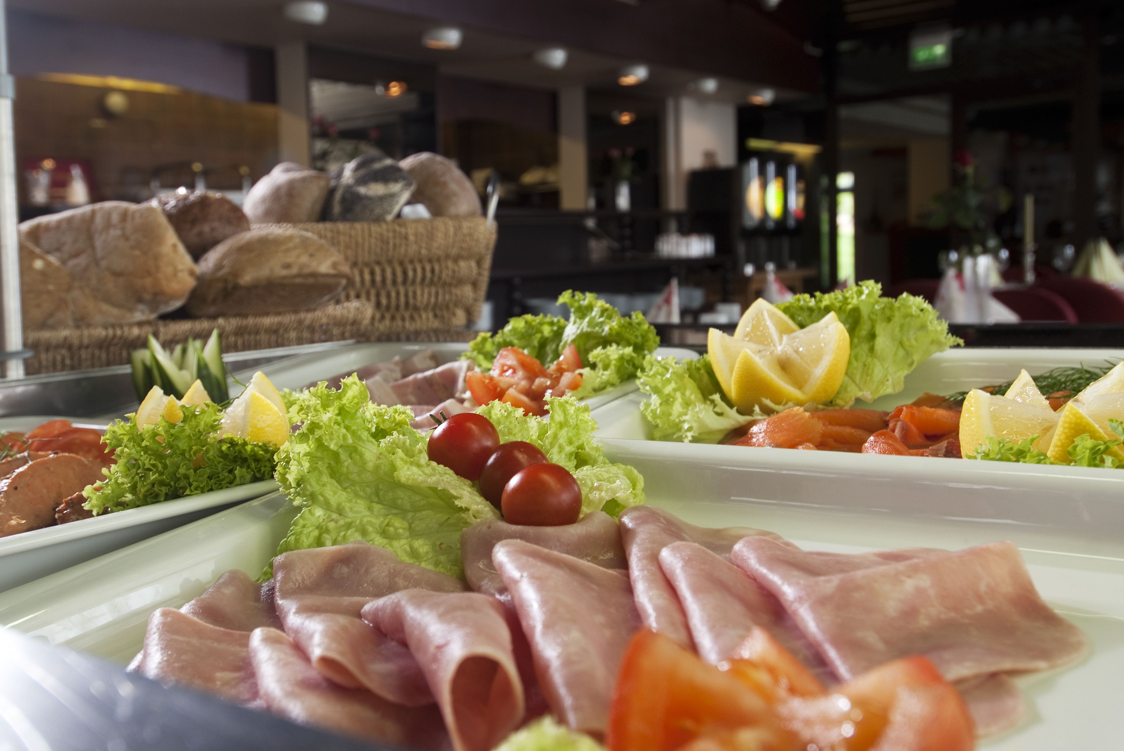 A buffet with various meats, cheeses, and fresh vegetables.