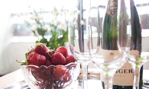 Ein Tisch mit Erdbeeren in einer Schale, einer Champagnerflasche und Weingläsern.