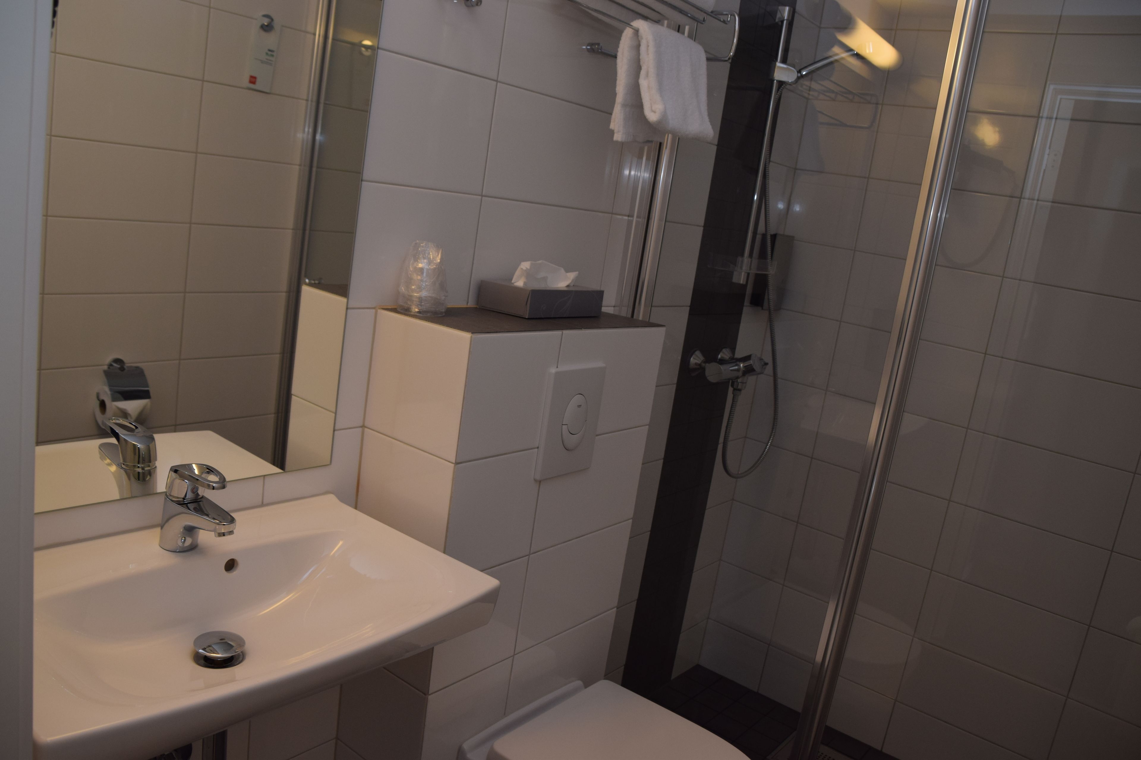 A modern bathroom with a sink, mirror, and shower.