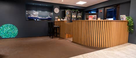 A reception area with a wooden counter, a clock, and a ship model on the wall.
