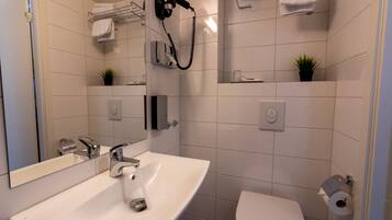 A modern bathroom with a sink, mirror, towel rack, and toilet.