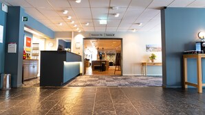 En hotellobby med en receptionsdisk, en restaurang/bar och en toalett som är lätt att hitta.