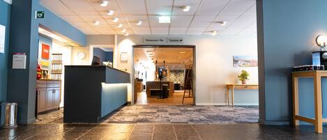 A hotel lobby with a reception desk, a restaurant/bar, and a visible toilet.