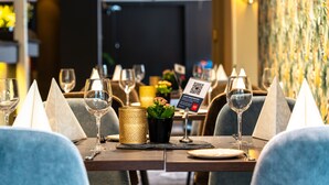 Ett restaurangbord dukat med vinglas, ett ljus och en skylt med en QR-kod för gästregistrering.