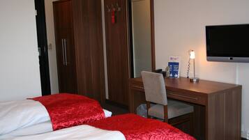 A hotel room with two beds, a desk, a chair, a TV, and a wardrobe.