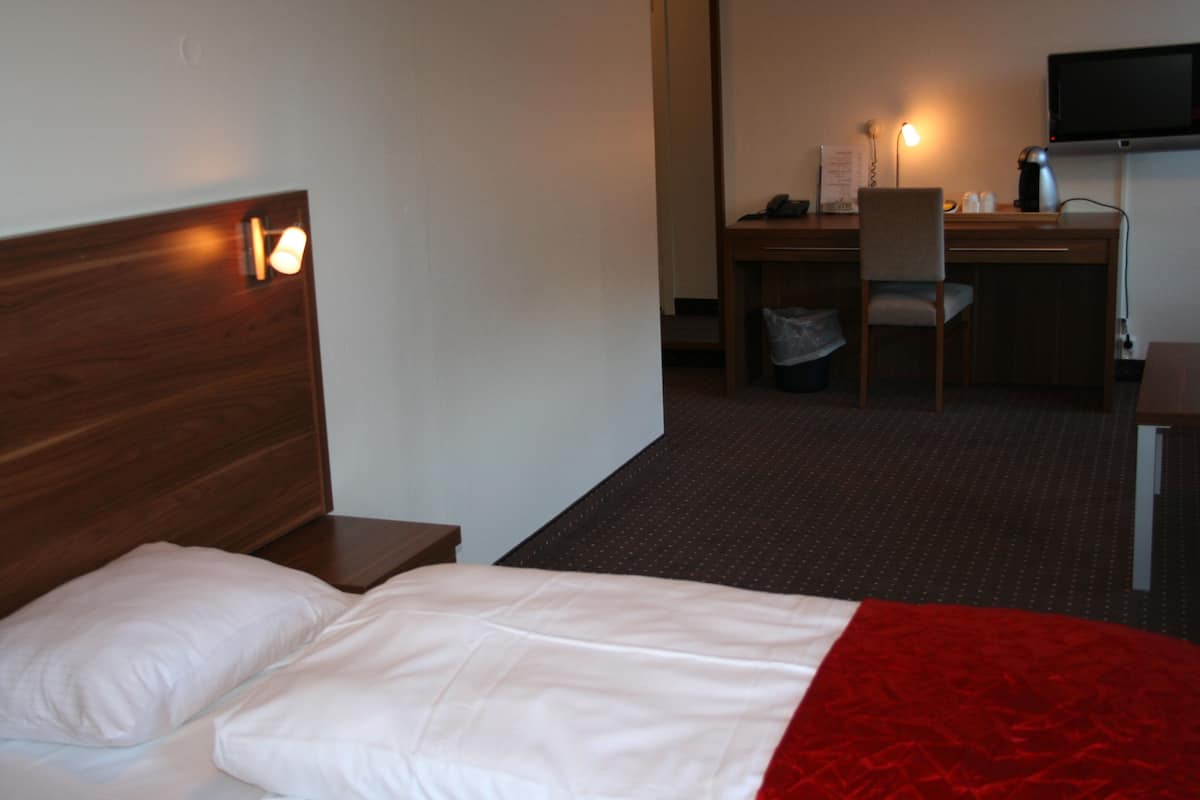 A hotel room with a bed, a desk, and a television.