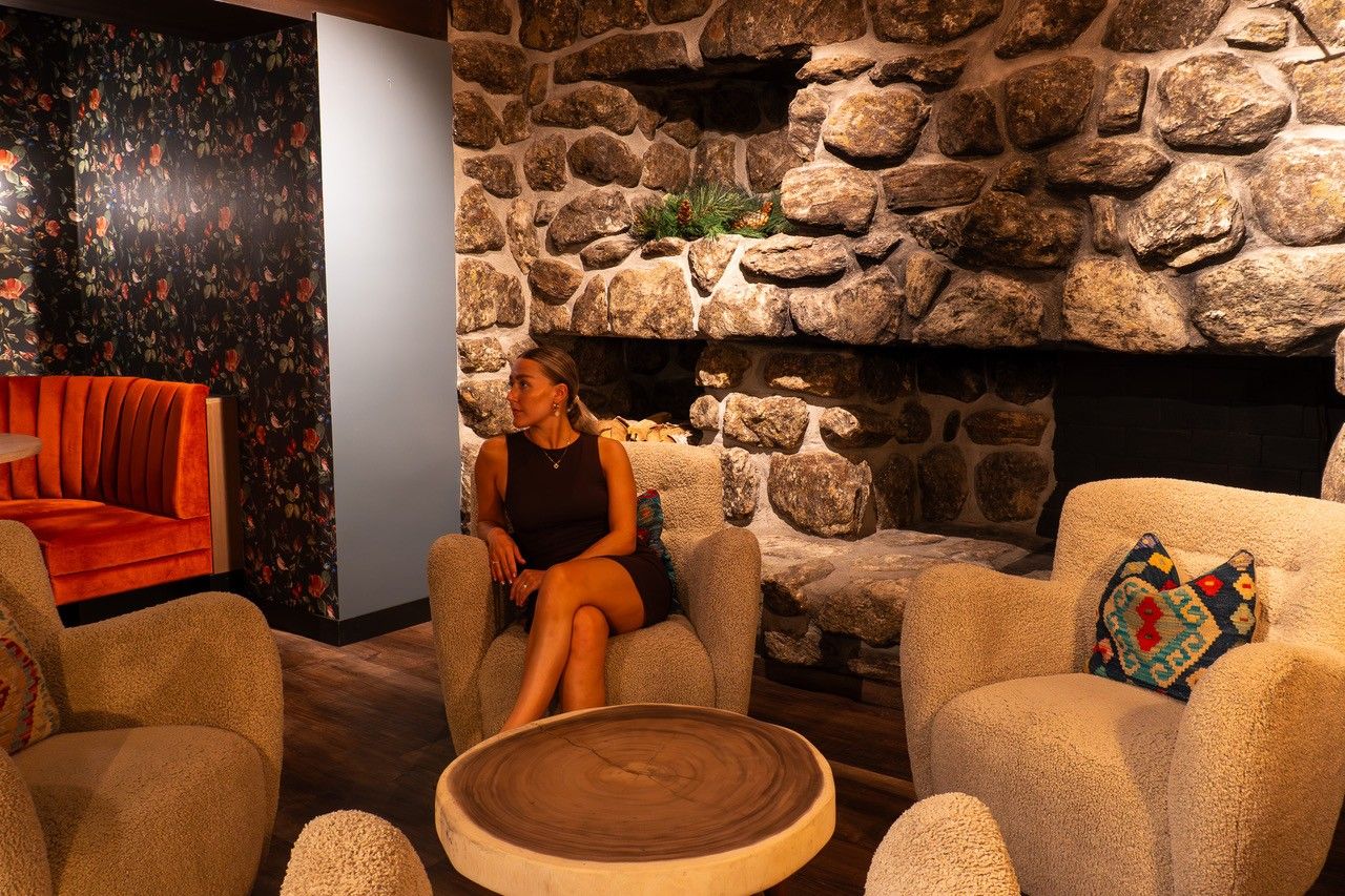 Una habitación con chimenea de piedra, sofá rojo y pared con diseño.