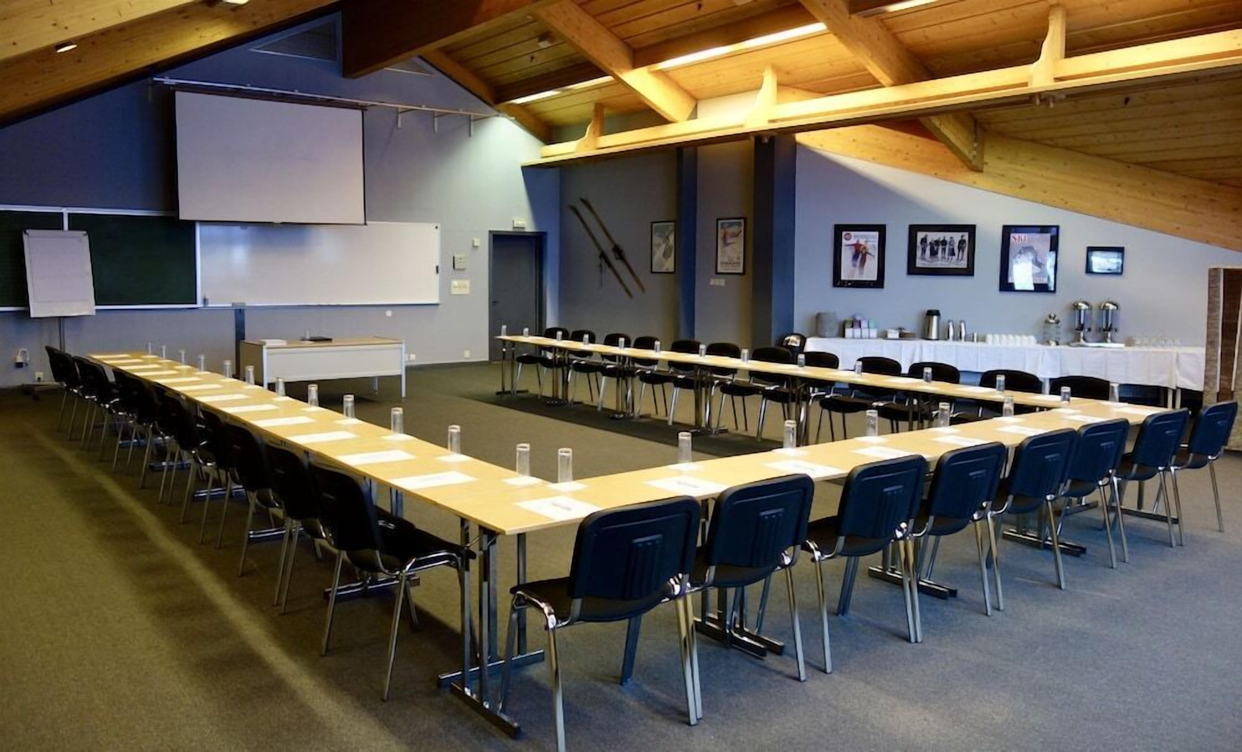 A conference room with a long table and chairs, a whiteboard, and a projector screen.