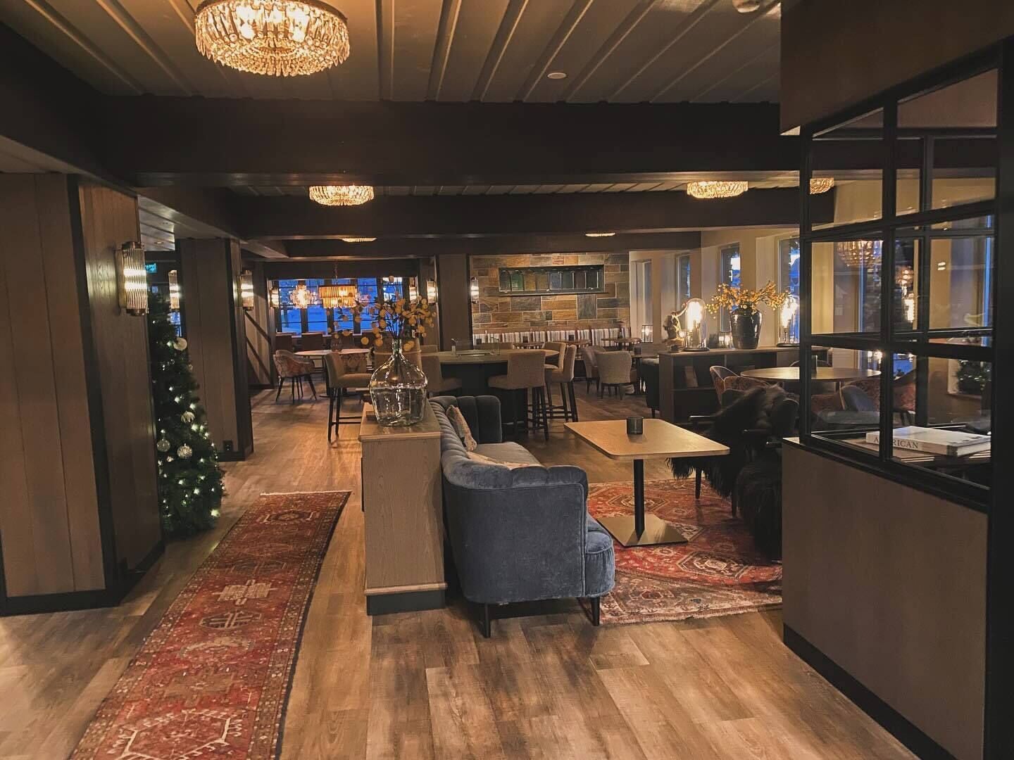 A modern lounge area with a Christmas tree, seating, and a bar.