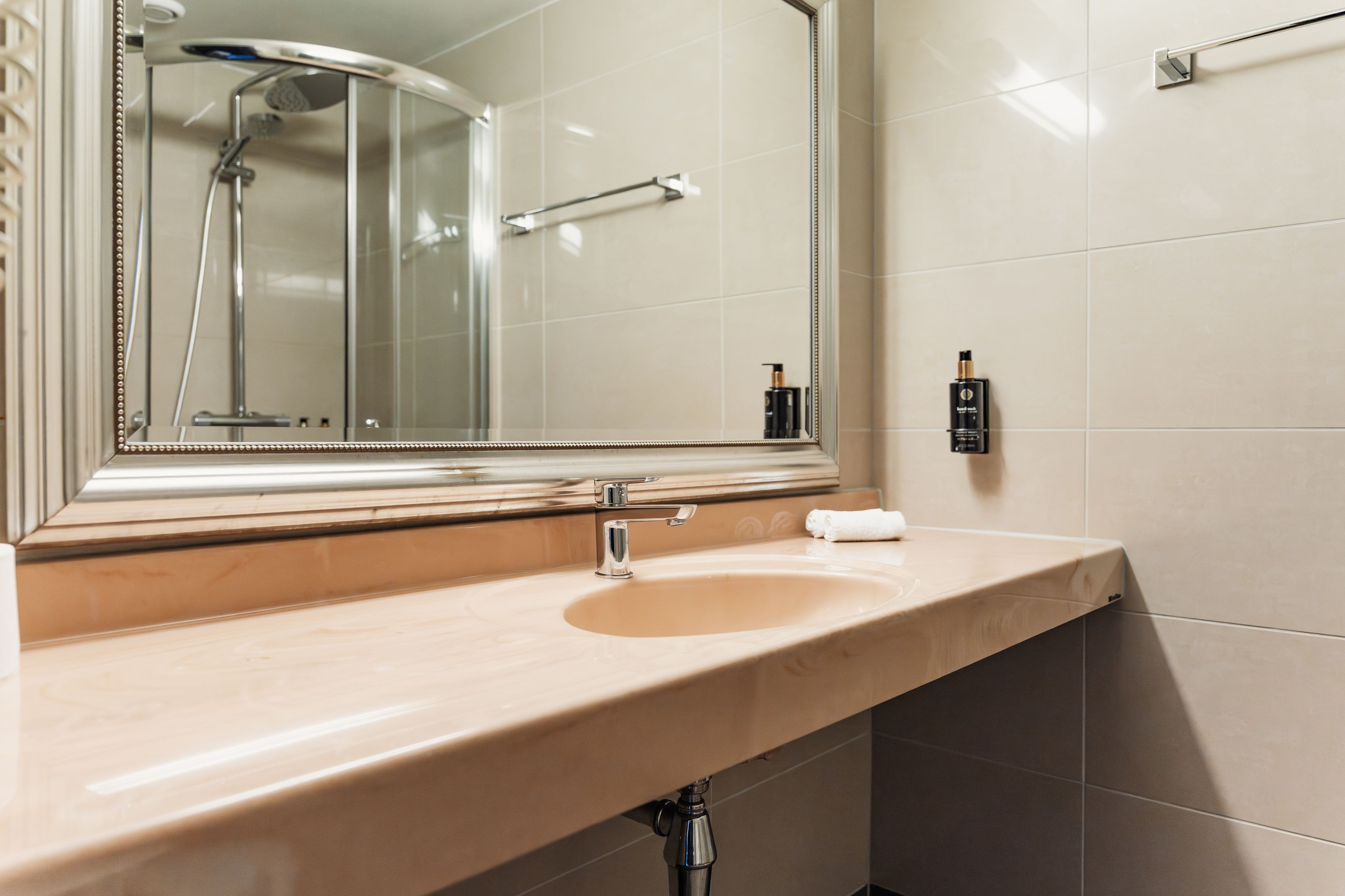 A bathroom with a beige sink, a mirror, and a shower.