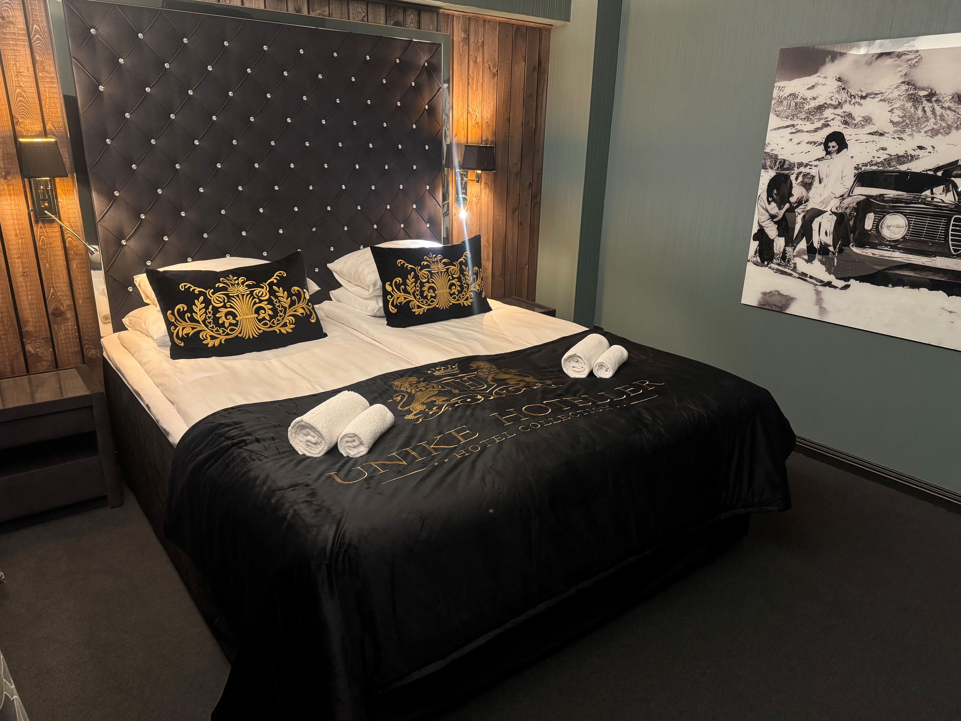 Una habitación de hotel con una cama grande, un cabecero con diseño de diamantes y un cuadro colgado en la pared.