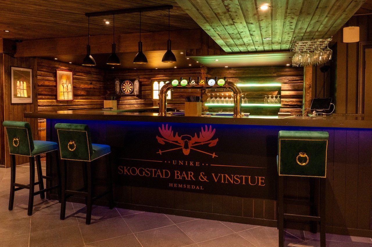 A bar area with wooden walls, a bar counter, and two bar stools.