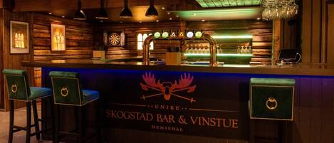 A bar area with wooden walls, a bar counter, and two bar stools.