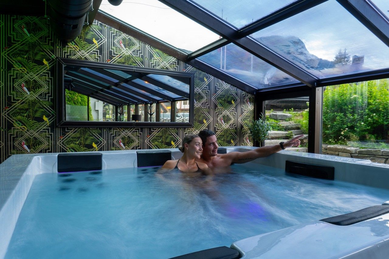 A hot tub with a geometric patterned wall and a view of greenery outside.