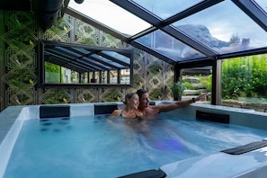 A hot tub with a geometric patterned wall and a view of greenery outside. - Skogstad Hotell - Unike Hoteller (Hemsedal)