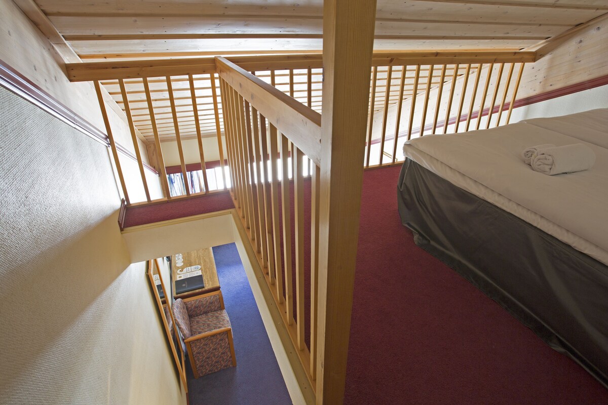 A room with a bunk bed, a small table, and a chair.