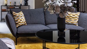 Una sala de estar moderna con un sofá seccional gris, una mesa de centro negra y jarrones decorativos.
