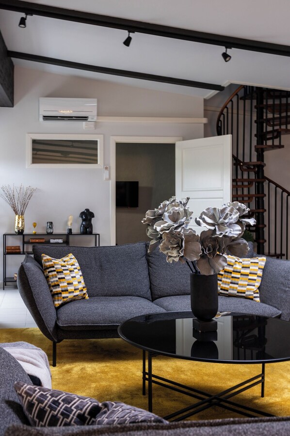 Una sala de estar moderna con un sofá seccional gris, una mesa de centro negra y jarrones decorativos.
