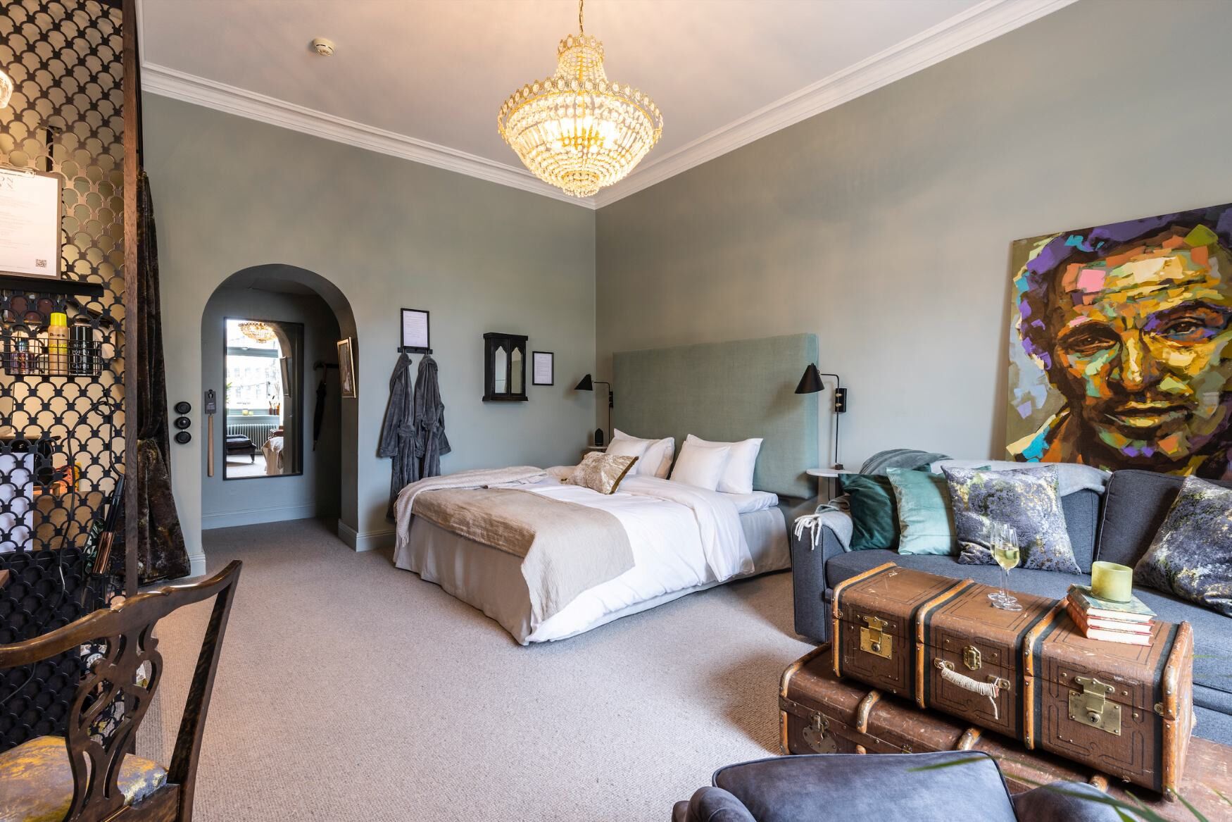 Une chambre à coucher avec un grand lit, un lustre, un canapé et un tableau.
