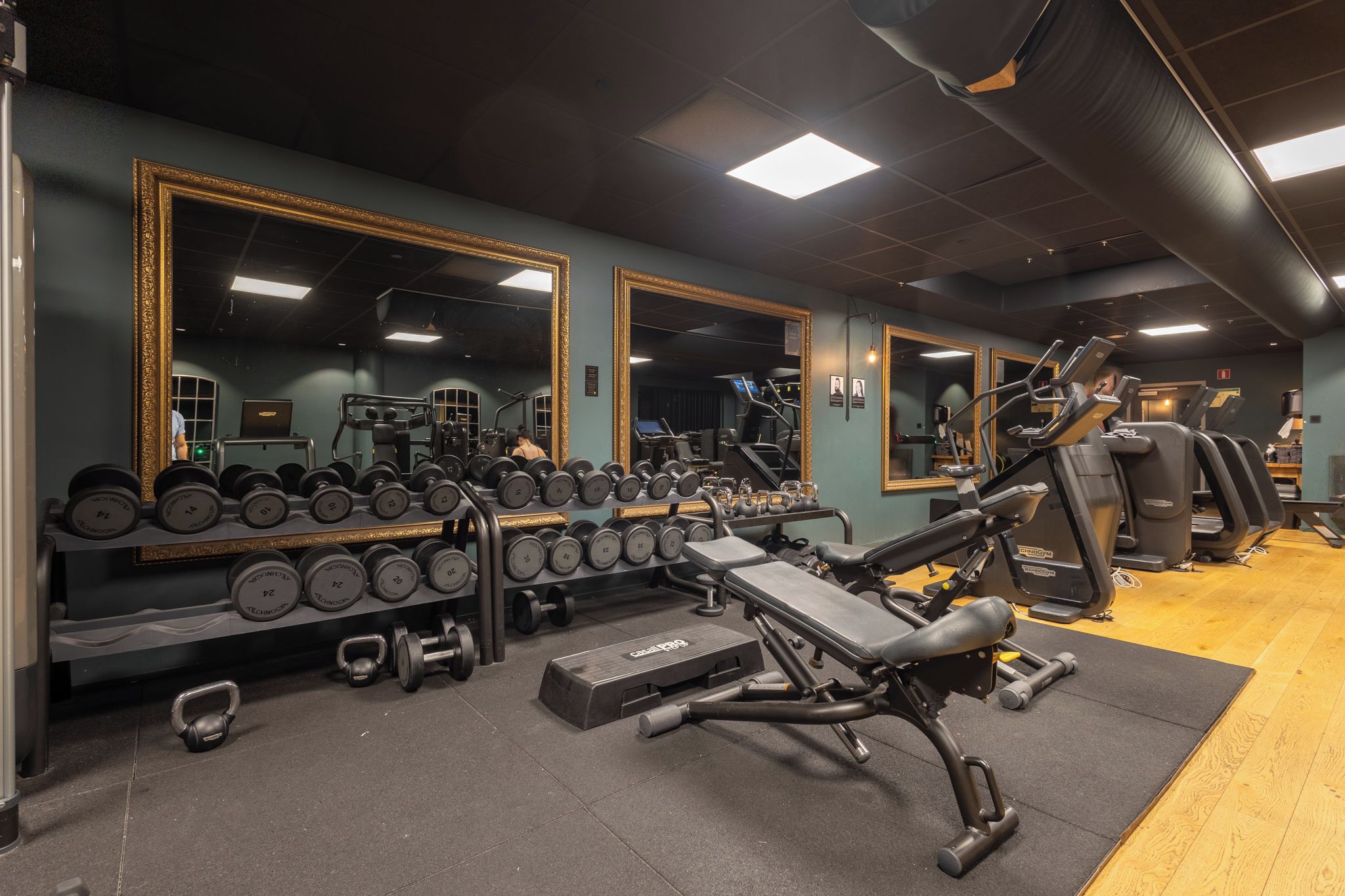 A gym with exercise equipment, mirrors, and weightlifting accessories.