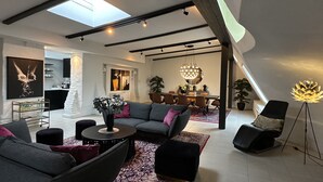 Una sala de estar moderna con techo alto, tragaluces y un comedor con candelabro.