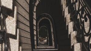 Una escalera con barandilla de hierro forjado y paredes de piedra.