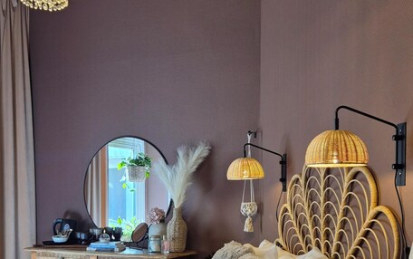 A bedroom with a bed, a dresser, a mirror, and two wall-mounted lamps.