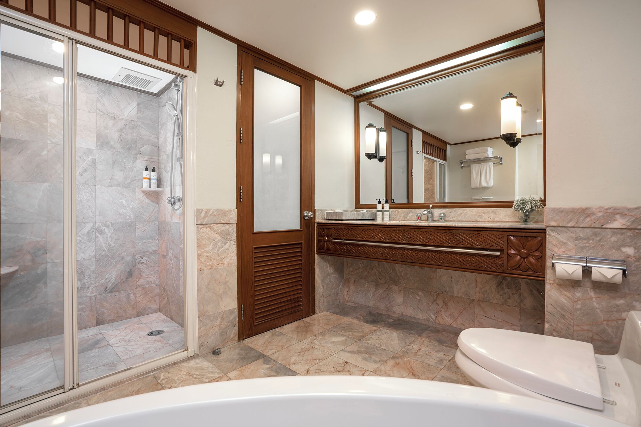 Une salle de bain moderne dotée d’une douche à parois de verre, d’une baignoire sur pieds et d’un meuble-lavabo avec un grand miroir.