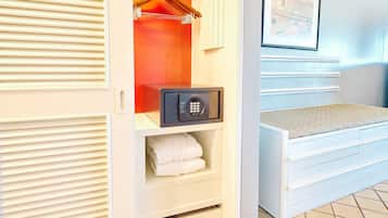 Una habitación de hotel con vestidor, caja fuerte y cama con cabecera.
