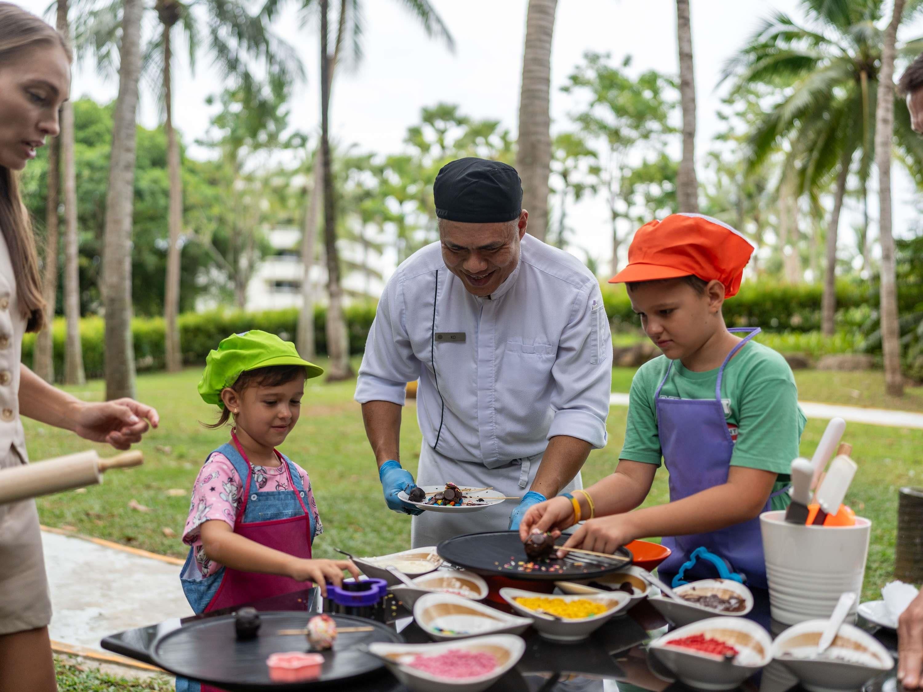 A group of people preparing food outdoors with a table full of ingredients and cooking utensils.