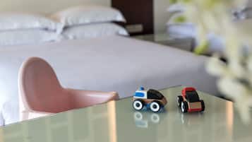 A hotel room with a bed, a small table with toys, and a chair.