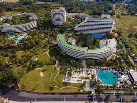 A resort with multiple circular buildings, a central pool, and lush greenery.