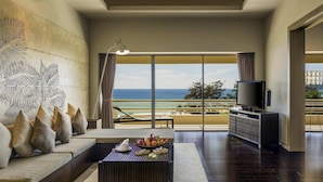 A spacious room with a large window offering a view of the ocean, a sofa, a coffee table with fruit, and a flat-screen TV. - Pullman Phuket Karon Beach Resort (Karon)